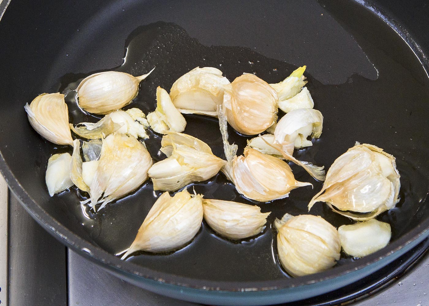 鍋に皮付きのにんにくとオリーブ油を入れ、弱火にかけ、にんにくの上下を返しながら火を通す。