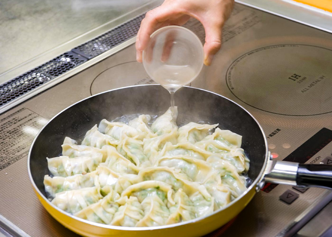 ギョーザの半分の高さまで湯を入れて、ふたをして強火で蒸し煮する。ギョーザに火が通ったら、ふたで押さえて湯を切る。