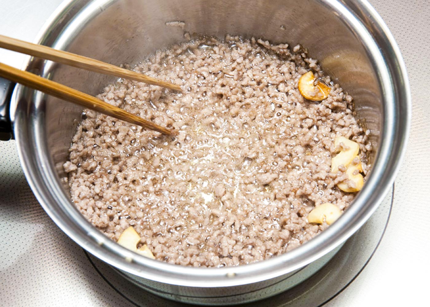 鍋にごま油とにんにくを入れ、弱火にかける。いい香りが立ってきたら、豚ひき肉を加え、強火で炒める。